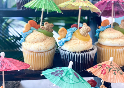 A table topped with cupcakes covered in umbrellas.