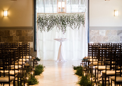 A wedding ceremony with candles and greenery.
