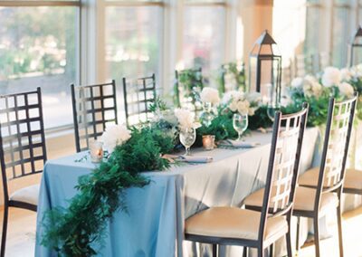 Sunlit reception table with blue cloth and garland