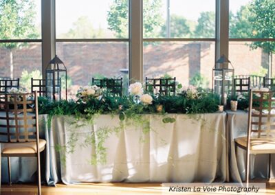 Sunlit head table with lush green garland